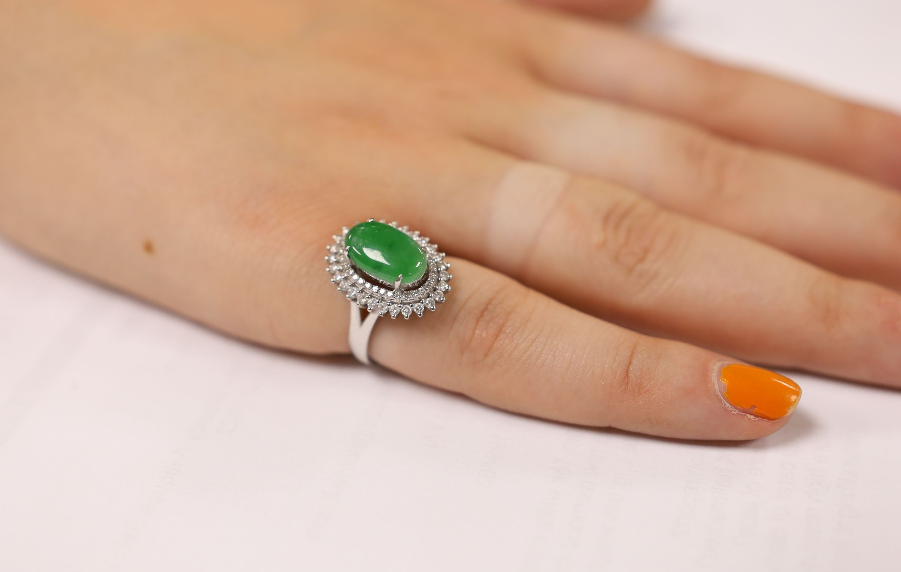 A modern 18k white metal, cabochon jade and two row diamond chip set oval cluster ring size L, gross weight 6.4 grams.